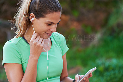 Buy stock photo Shot of a young woman listening to music while exercising in the outdoors