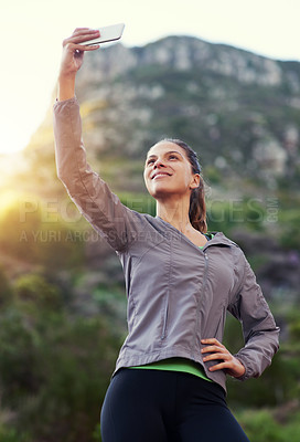 Buy stock photo Shot of a young woman taking a selfie while out for a trail run
