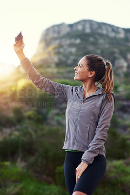 Buy stock photo Shot of a young woman taking a selfie while out for a trail run