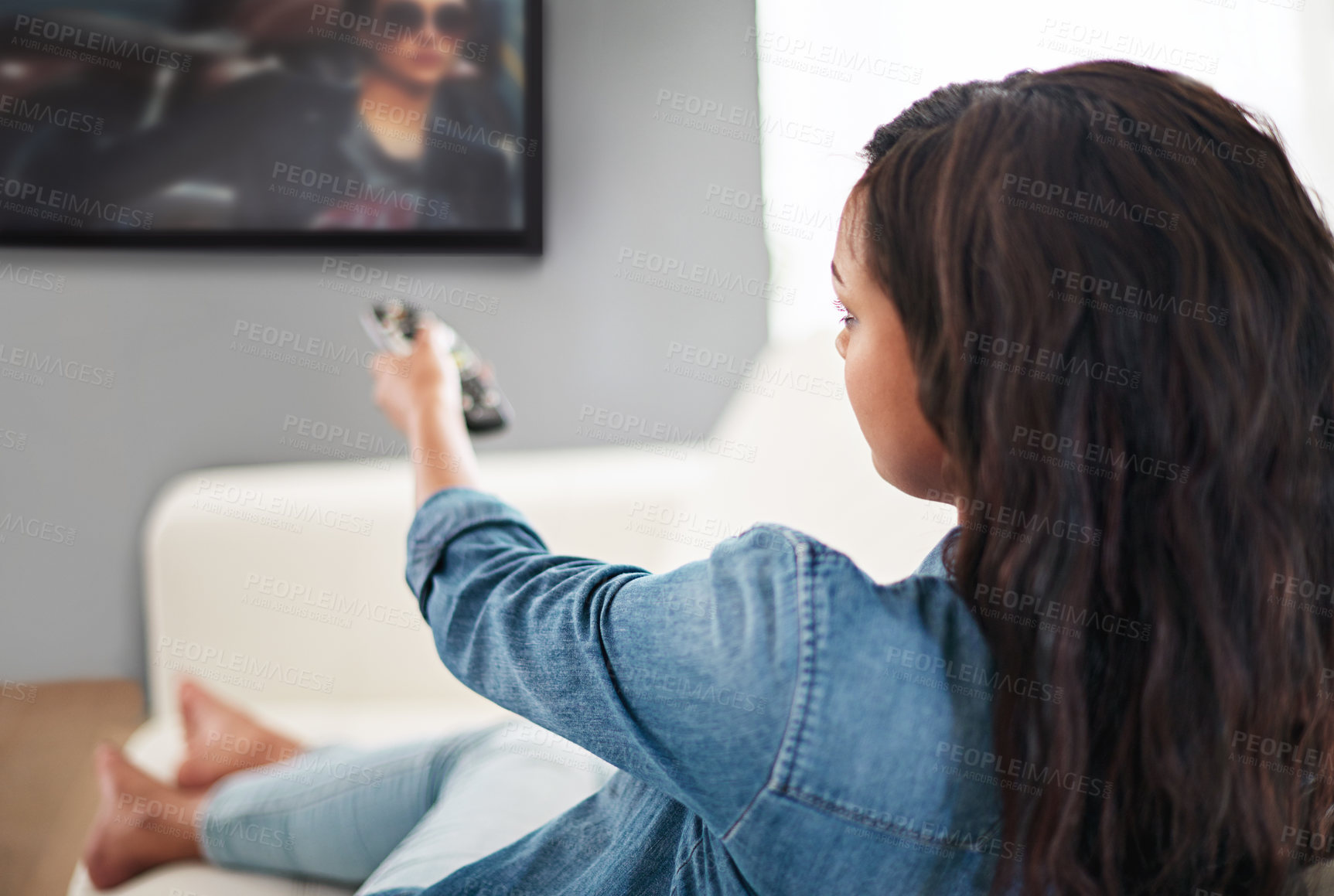 Buy stock photo Shot of a young woman watching television at home
