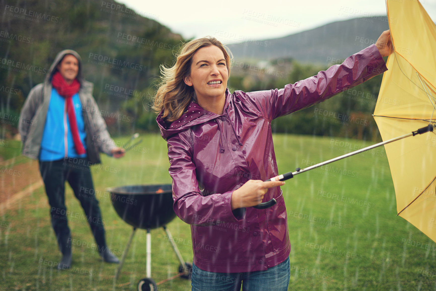 Buy stock photo Shot of a couple trying to barbecue in the rain