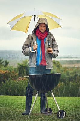 Buy stock photo Shot of a man barbecuing in the rain