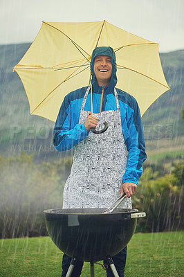 Buy stock photo Shot of a man happily barbecuing in the rain