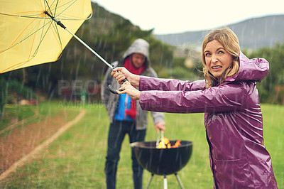 Buy stock photo Shot of a couple trying to barbecue in the rain