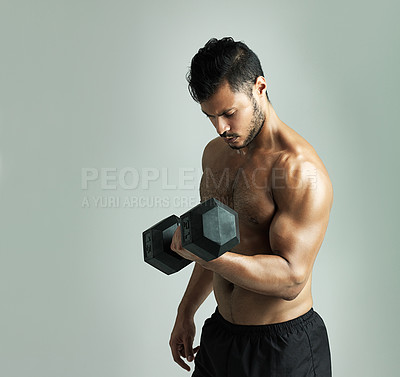 Buy stock photo Studio shot of a young man working out with a dumbbell against a gray background
