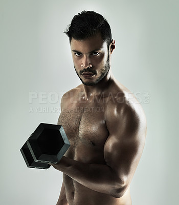 Buy stock photo Studio shot of a young man working out with a dumbbell against a gray background