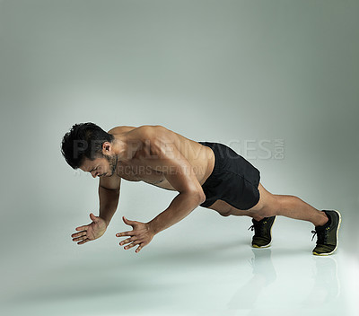 Buy stock photo Studio shot of a young man doing a clap pushup against a gray background