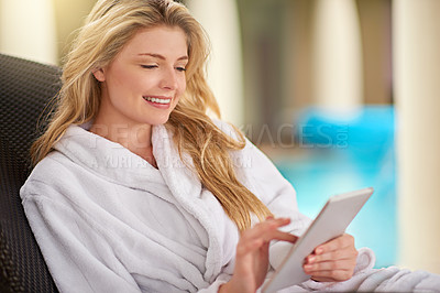 Buy stock photo Shot of a young woman relaxing with her digital tablet at a day spa