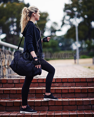 Buy stock photo Shot of a sporty young woman carrying a gym bag