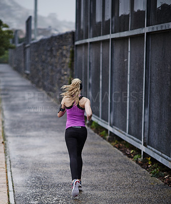 Buy stock photo Rearview shot of a young woman running along a path