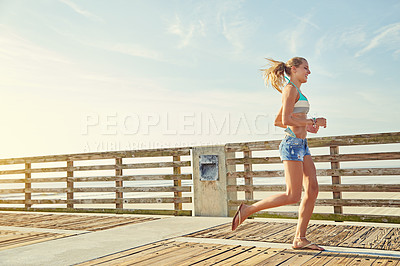 Buy stock photo Shot of a young woman in a bikini on a walkway near the beach