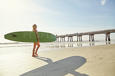 Buy stock photo Rearview
shot of an attractive young woman carrying her surfboard on the beach