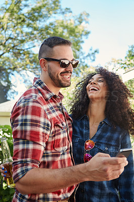 Buy stock photo Shot of a young man sharing something on his cellphone with his girlfriend