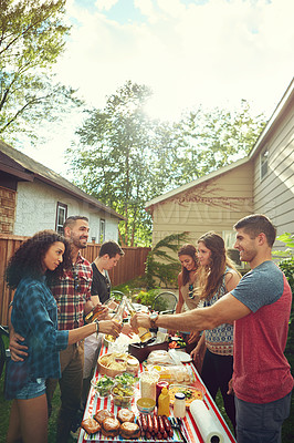 Buy stock photo Shot of a group of friends having lunch in their backyard