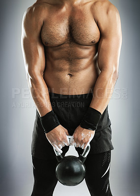 Buy stock photo Cropped studio shot of a fit young man working out with a kettlebell