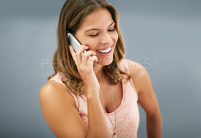Buy stock photo Funny, phone call and happy woman talking in studio for story, gossip or news discussion isolated on a gray background. Mobile, smile and laughing model in conversation, chat and listening to contact