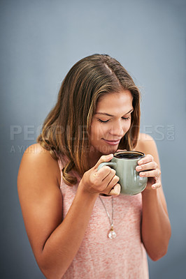 Buy stock photo Studio shot of a young woman drinking a cup of coffee against a gray background