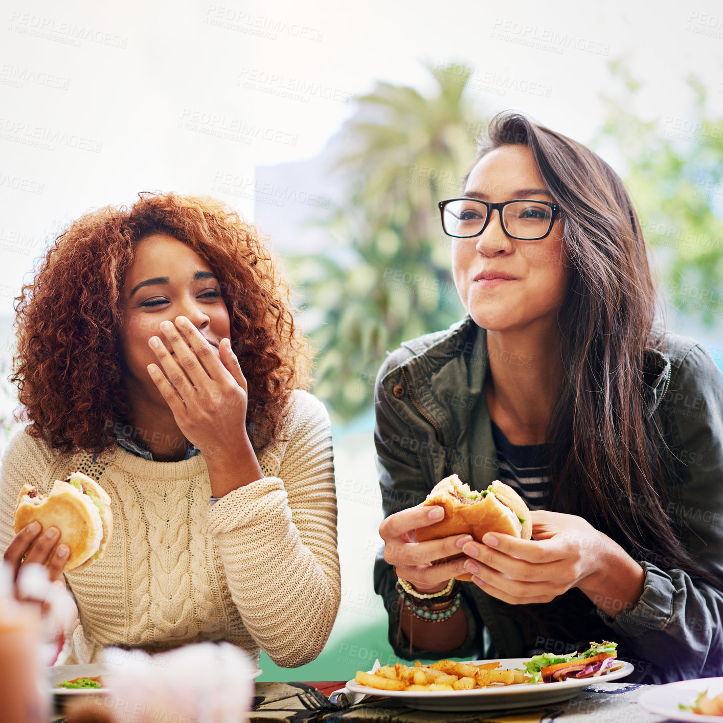 Buy stock photo Cropped shot of two girlfriends eating burgers outdoors