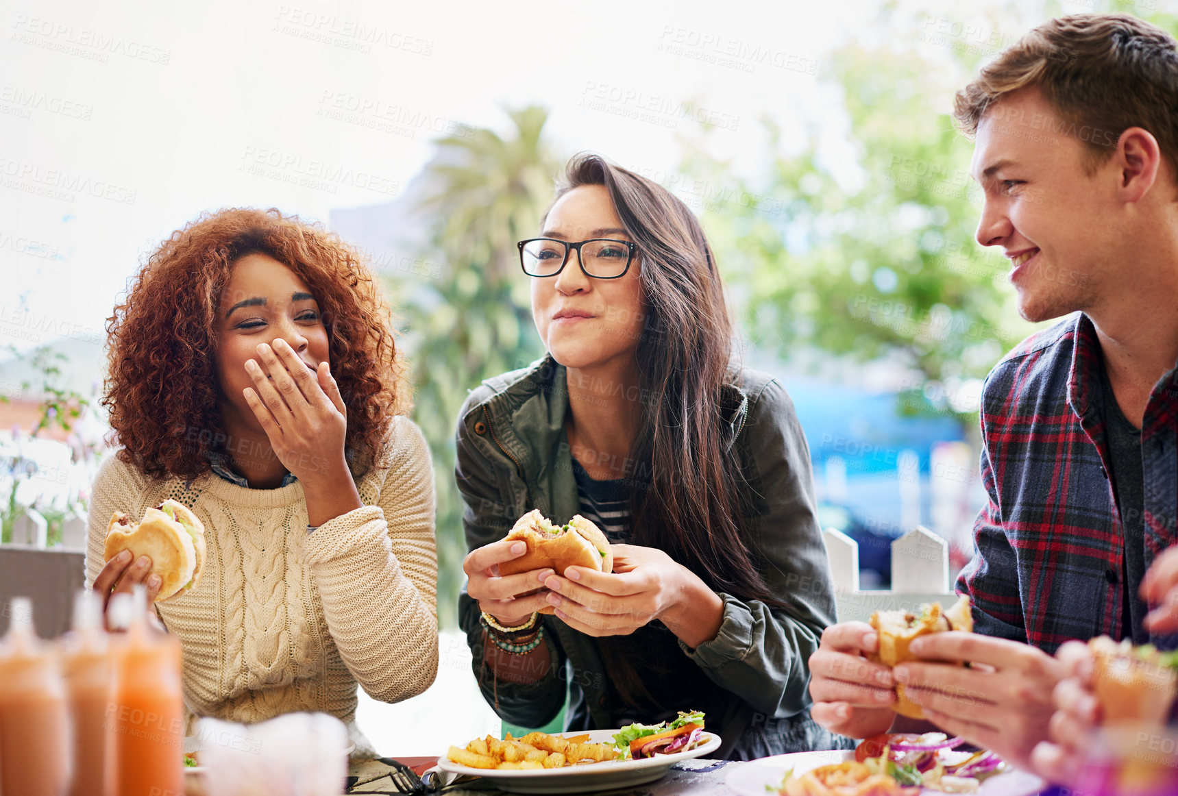 Buy stock photo Cropped shot of three friends eating burgers outdoors