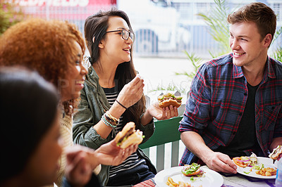Buy stock photo Cropped shot of a group of friends eating burgers outdoors