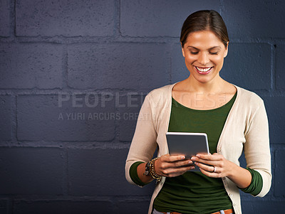 Buy stock photo Shot of a young woman using a digital tablet against a brick wall background