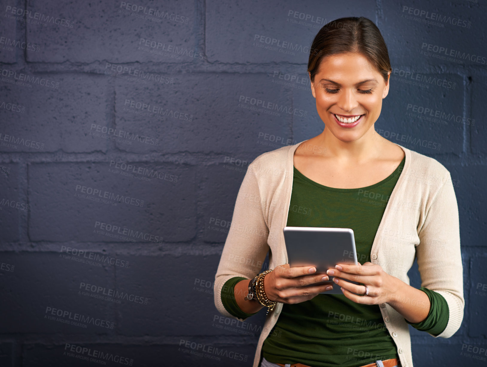 Buy stock photo Shot of a young woman using a digital tablet against a brick wall background