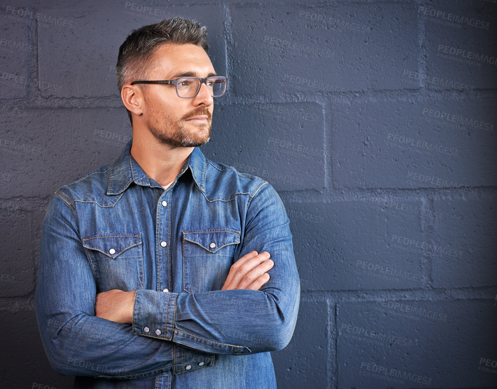 Buy stock photo Shot of a confident man posing against a brick wall background
