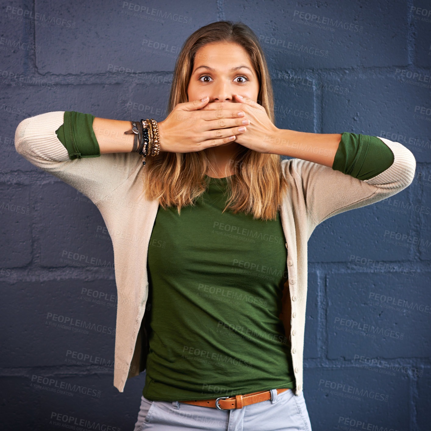 Buy stock photo Shot of a young woman covering her mouth against a brick wall background