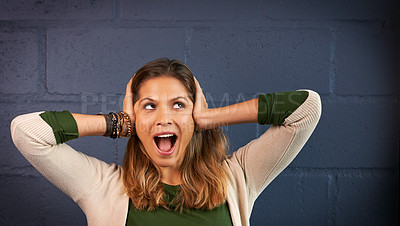 Buy stock photo Shot of a young woman covering her ears against a brick wall background