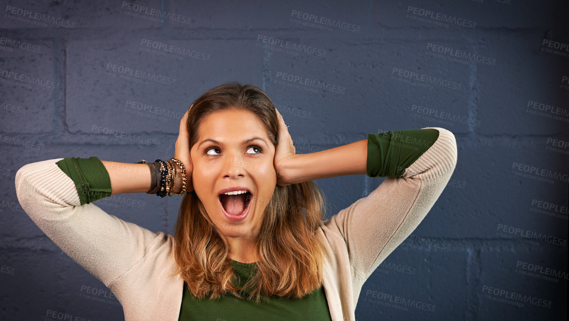 Buy stock photo Shock, excited and woman by wall for wow, omg or amazed facial expression for good news. Happy, surprise and female person covering ears for loud noise with goofy joke by gray brick background.