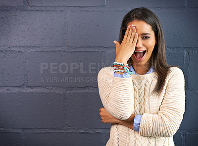 Buy stock photo Shot of a young woman covering her eye against a brick wall background