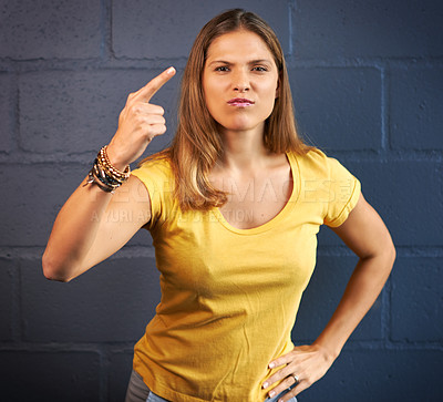 Buy stock photo Cropped portrait of a young woman looking angry against a brick wall background