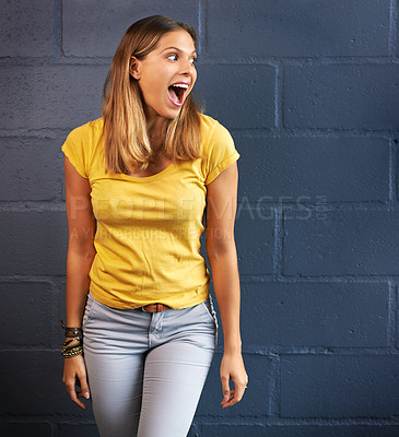 Buy stock photo Shot of a young woman looking amazed against a brick wall background