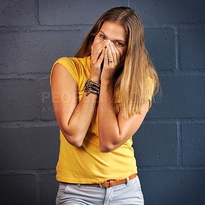 Buy stock photo Shot of a young woman covering her mouth against a brick wall background