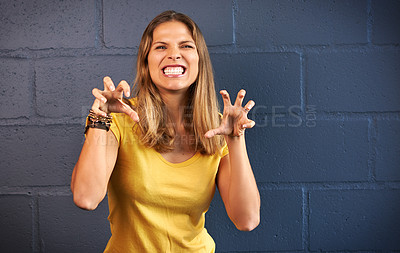 Buy stock photo Portrait of a young woman making a growling gesture against a brick wall background