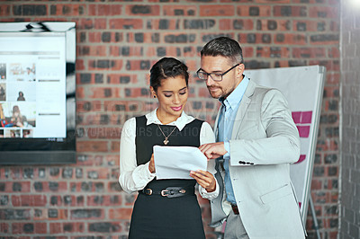 Buy stock photo Cropped shot of two businesspeople looking over some paperwork in the office