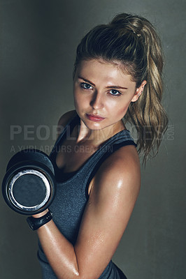 Buy stock photo Shot of a young woman lifting dumbbells against a gray background