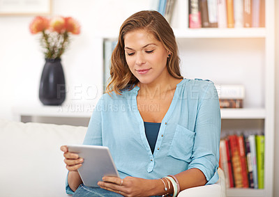 Buy stock photo Shot of a young woman using her digital tablet at home