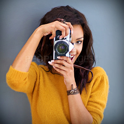 Buy stock photo Studio portrait of a young woman using a vintage camera against a gray background