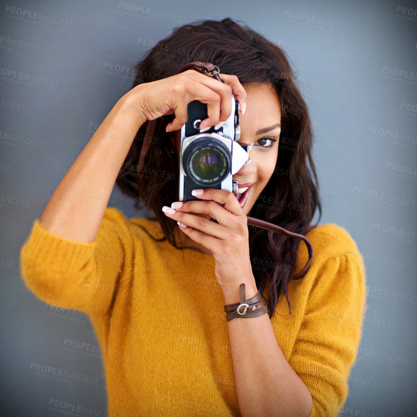 Buy stock photo Studio portrait of a young woman using a vintage camera against a gray background