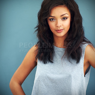 Buy stock photo Studio portrait of a young woman posing against a blue background
