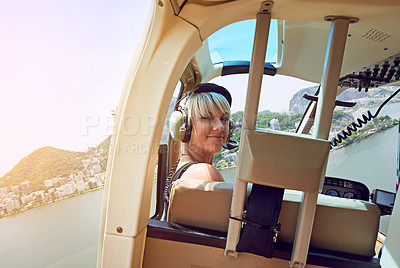 Buy stock photo Shot of a young woman in the passenger seat of a helicopter flying over Rio