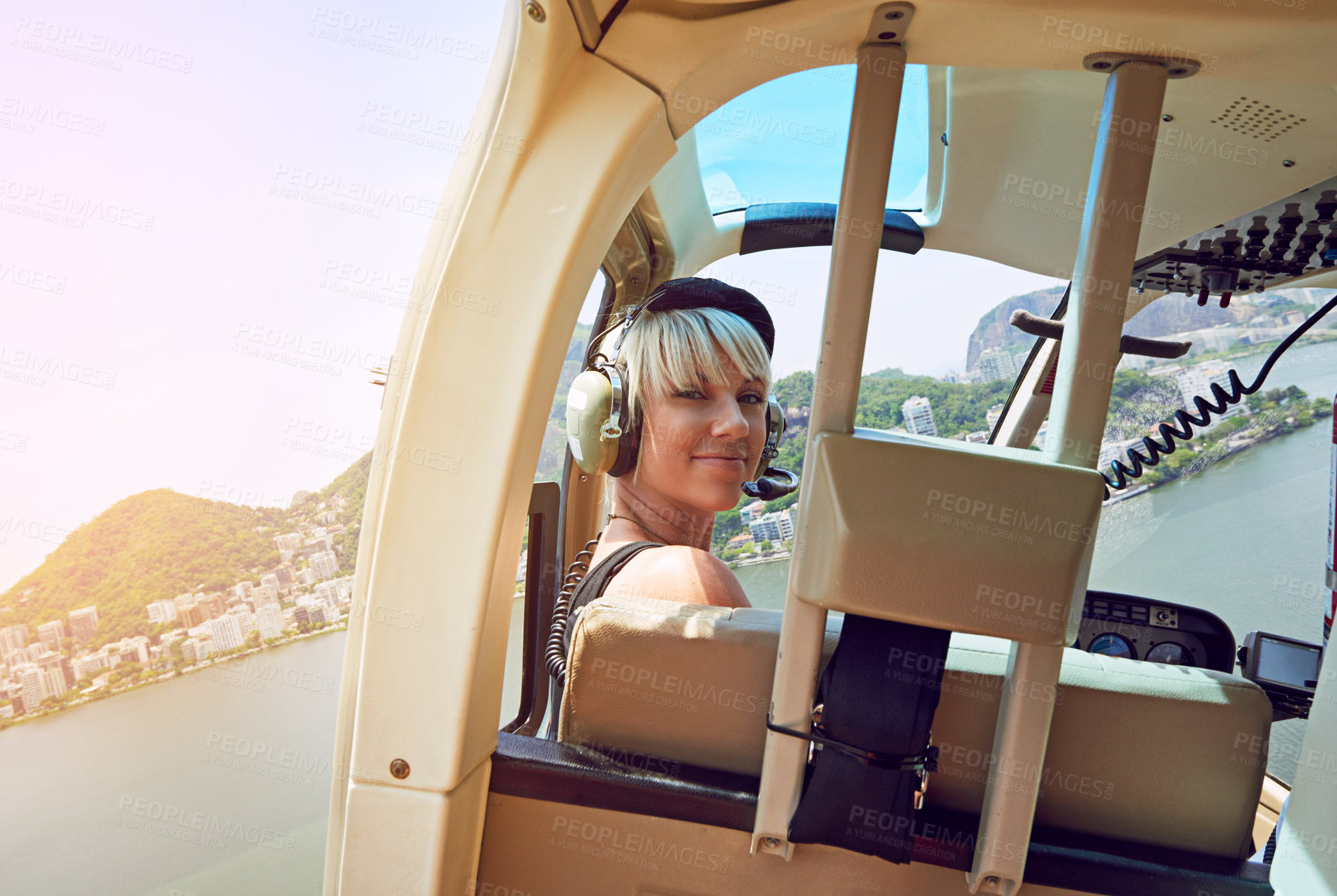 Buy stock photo Shot of a young woman in the passenger seat of a helicopter flying over Rio