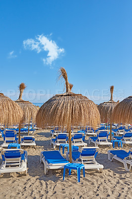 Buy stock photo Beach, chairs and blue sky with straw umbrellas of villa, village or outdoor vacation in malaga. Empty, island or tropical shore with shade and seating area for holiday getaway by sea coast in spain