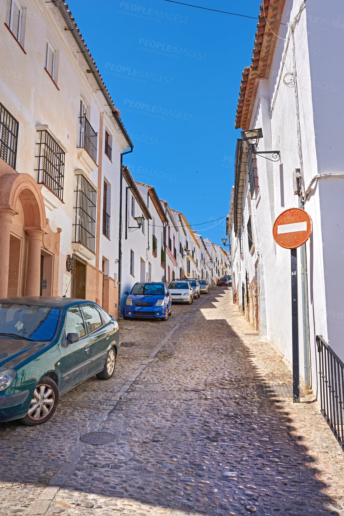 Buy stock photo Buildings, town and road outside with architecture, travel and exploration with blue sky and aesthetic. Infrastructure, village and street outdoor for holiday, alley and tourist location in Spain