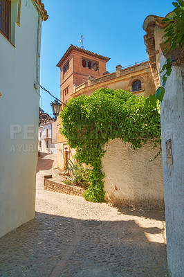 Buy stock photo Ancient, houses and buildings with narrow street for wall structure, travel location and history architecture. Alley, neighborhood and city view, blue sky and plant growth of vintage culture in Spain