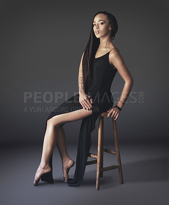 Buy stock photo Studio shot of a beautiful young woman sitting on a chair against a gray background