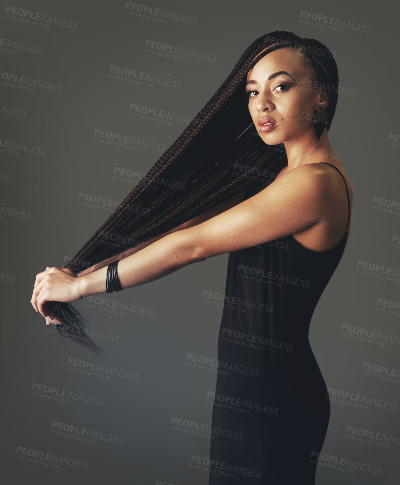 Buy stock photo Studio portrait of a beautiful young woman tugging at her hair against a gray background