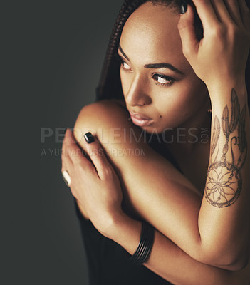 Buy stock photo Studio shot of a beautiful young woman with a tattoo on her arm against a gray background