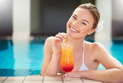 Buy stock photo Portrait of an attractive young woman sipping a cocktail by the pool